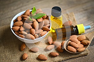 Almond oil and Almonds nuts on bowl, Delicious sweet almonds oil in glass bottle, roasted almond nut for healthy food and snack