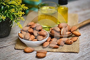 Almond oil and Almonds nuts on wooden, Delicious sweet almonds oil in glass, roasted almond nut for healthy food and snack organic