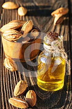 Almond oil bottle and almond nuts on wooden background.