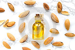 Almond oil and nuts on a white marble background. The concept of healthy vegan food and natural cosmetics.