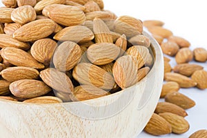 Almond in wooden bowl on white background isolated.