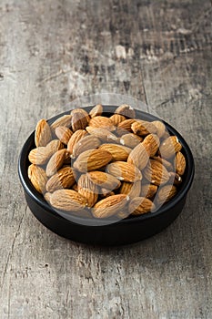 Almonds in black bowl on wood