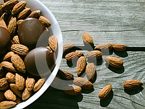 Almonds and dark chocolate in a bowl on a wooden table. Healthy snack