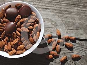 Almonds and dark chocolate in a bowl on a wooden table. Healthy snack