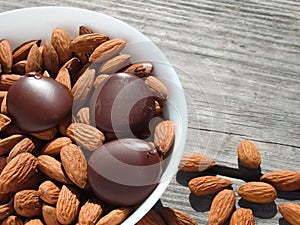 Almonds and dark chocolate in a bowl on a wooden table. Healthy snack