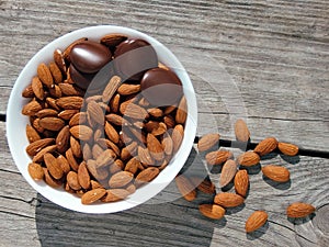 Almonds and dark chocolate in a bowl on a wooden table. Healthy snack