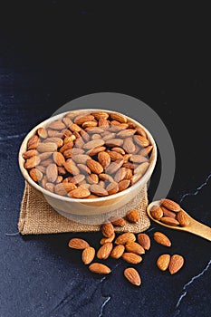 Almonds on dark stone table with wood spoon photo