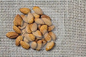 Almonds in detail. Handful or portion of almonds on jute fabric in top view