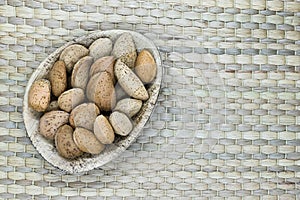 Almonds with the Nutshell in Eco Natural Banana Leaf Plate on Natural Bamboo Mat Surface with Free Space