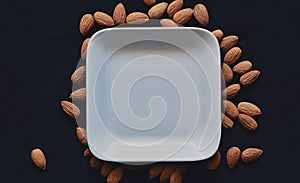 Almonds outside white plate against black background