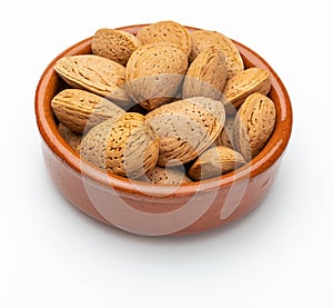 Almonds with shell in clay bowl.