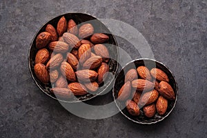 Almonds in two bowls on dark backgrounds