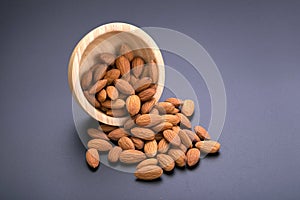 Almonds in wooden bowl on a black background