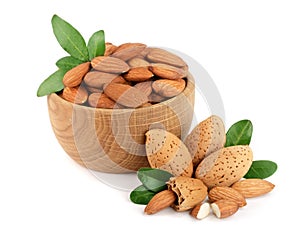 Almonds in a wooden bowl with leaves isolated on white background