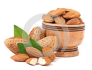 Almonds in a wooden bowl with leaves isolated on white background