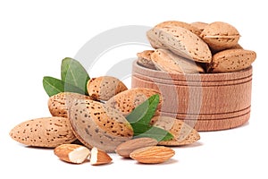 Almonds in a wooden bowl with leaves isolated on white background