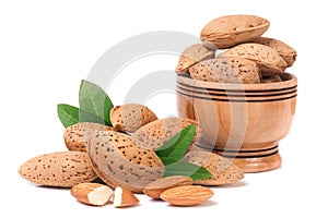 Almonds in a wooden bowl with leaves isolated on white background