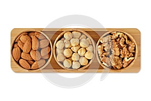 Almons, hazelnuts and walnuts in wooden bowls on white background