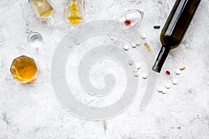 Alocohol abuse and alcoholism treatment concept. Glasses, bottles and medcine pills on light grey background top view