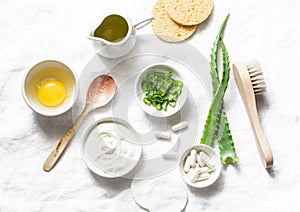 Aloe face mask ingredients -aloe, yogurt, egg, olive oil and beauty accessories on light background, top view. Home recipe