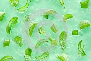 Aloe gel background with aloe slices. Cut slices of aloe in transparent cosmetic aloe gel. Flat lay.