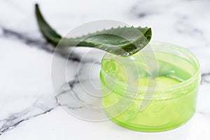 Aloe leaf and gel on a marble background with copy space. Moisturizing, recovery and caring for the skin.