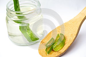 Aloe vera cut on wooden spoon and in jar on white