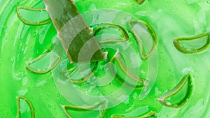 Aloe Vera gel background. Green cream gel moisturizer, cosmetic texture with slices of Aloe leaf, backdrop