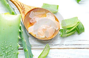 Aloe Vera gel closeup on white wooden background. Organic sliced aloevera leaf and gel, natural organic cosmetic ingredients