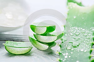 Aloe Vera gel closeup on white wooden background. Organic sliced aloevera leaf and gel, natural organic cosmetic ingredients
