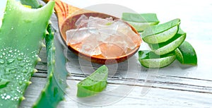 Aloe Vera gel closeup on white wooden background. Organic sliced aloevera leaf and gel, natural organic cosmetic ingredients