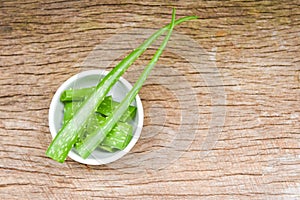 Aloe vera plant slice in bowl on rustic wood background - close up of fresh aloe vera leaf with gel natural herbs and herbal