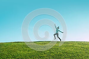 Alone asian Woman Jumping for Joy on a Grass Hill above horizon line One happy slim girl fly in a green field against blue summer