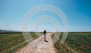 Alone backpacker traveler walks on contryside road in sultry aft photo