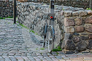 Alone bike is parked by a pole on the street in the ancient city