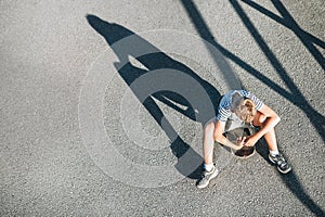 Alone boy without friends sits on skateboard. Child loneliness c