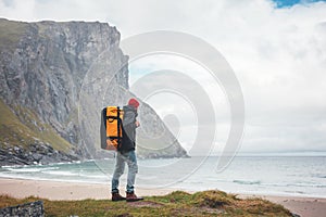 Alone brave male tourist standing in front of ord sea and great mountain rock photo