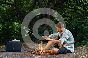 Alone businessman warms by the fire on lost island