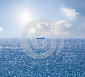 alone cargo ship among blue sea under sparkle sun