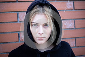 Alone girl portrait with hooded sweatshirt next urban street wall