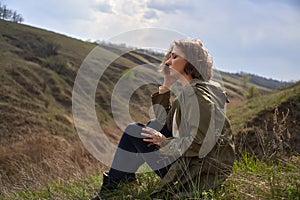 Alone girl is sad on nature hills background. Young woman  outdoor, post apocalyptic, epidemic, home violence