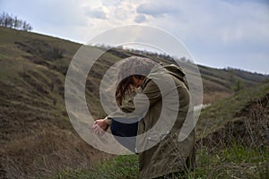 Alone girl is sad on nature hills background. Young woman  outdoor, post apocalyptic, epidemic, home violence