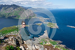 Alone happy woman hiker enjoys the view on cliff edge of lofoten islands, in Norway, Reinebringen