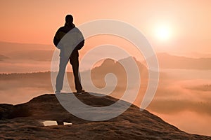 Alone hiker standing on top of a mountain and enjoying sunrise photo