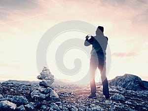 Alone hiker takes phone photo in mountains. Man on Alps mountain peak.View to purple sky