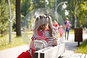 Alone little girl with a backpack sitting on a bench in the Park