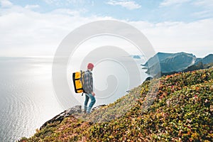 Alone man expeditor wearing professional backpack standing on the edge cliff mountain above sea and looking on epic high landscape