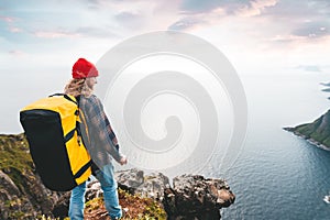 Alone man expeditor wearing professional backpack standing on the edge cliff mountain above sea and looking on epic high landscape