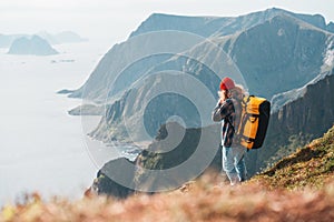 Alone man expeditor wearing professional backpack standing on the edge cliff mountain above sea and looking on epic high landscape