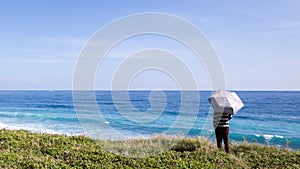 Alone man holding an umbrella stand at the beach